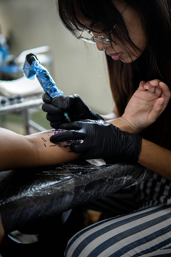 Gasttätowiererin arbeitet konzentriert an einem Tattoo in einem sauberen Tattoostudio in Siegburg